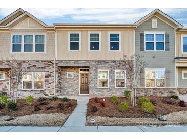 Two-story townhome with stone and siding accents, landscaping, and a walkway at 638 Sagecroft Ln, Indian Trail, NC 28079