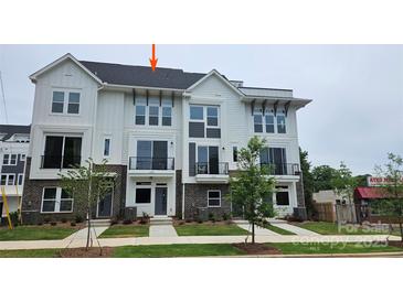 Beautiful three-story townhome with brick and Hardie board exterior, black railings, and professionally landscaped lawn at 1225 E 34Th St # Csw0419, Charlotte, NC 28205