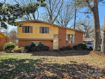 Charming front exterior featuring brick facade, mature trees, and a well-maintained lawn on a sunny day at 1608 Carfax Dr, Charlotte, NC 28216