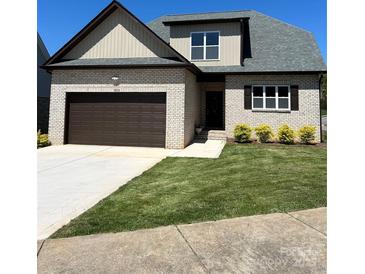 Charming brick home featuring a two-car garage, manicured lawn, and a welcoming entrance at 1033 12Th Avenue Nw Dr, Hickory, NC 28601