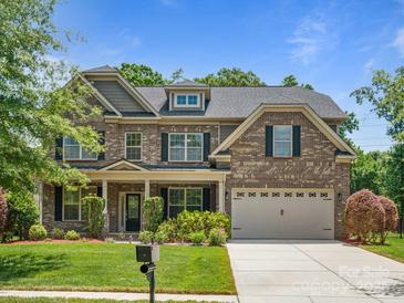 Two story brick home with a three-car garage and landscaped lawn at 4624 Pebble Run Dr, Matthews, NC 28105