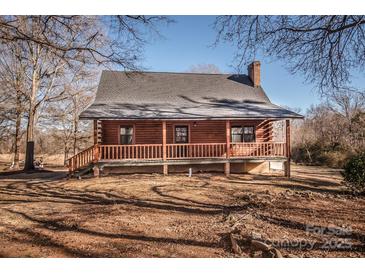 Rustic log cabin with a wrap-around porch and large yard at 604 N Central Ave, Locust, NC 28097