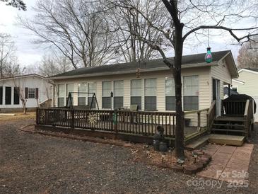 Cream-colored house with large windows, deck, and surrounding trees at 135/137 Indian Harbor Trl # E16/17, Mount Gilead, NC 27306