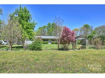 Beautiful landscaped front yard with mature trees and a charming wooden gazebo at 16415 Capps Rd, Charlotte, NC 28278