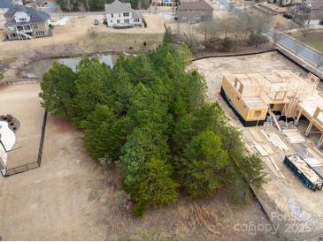 Aerial view of a home under construction surrounded by mature trees and a pond at 14108 Rhone Valley Dr, Charlotte, NC 28278