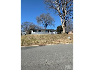 Ranch home with white brick exterior, covered porch, and landscaped yard at 3225 Cricketeer Dr, Charlotte, NC 28216