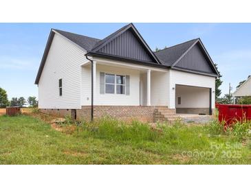 Charming exterior view of the home featuring white siding, black roof, covered porch, and an attached garage at 244 Little Wilkesboro Rd, Harmony, NC 28634