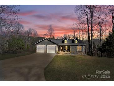 Charming home with a two-car garage, manicured lawn, and inviting front porch at twilight at 412 Wildlife Rd, Troutman, NC 28166