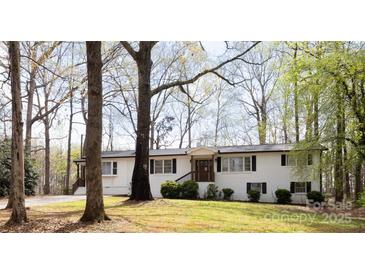 Charming white brick home with black shutters and a cozy front porch nestled among mature trees at 1035 Timberlane Dr, Lincolnton, NC 28092