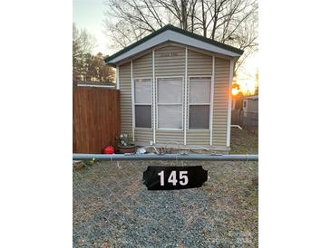 Tan mobile home with three windows and a black address marker at 145 Arrowood Trl # 61F, Mount Gilead, NC 27306