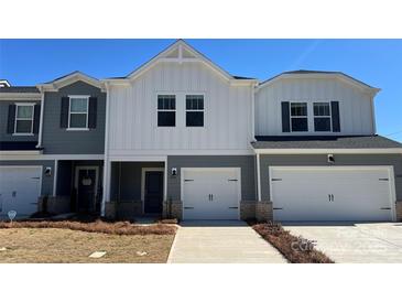 Charming townhome featuring a modern white and gray exterior with a one car garage and a well-maintained lawn at 1604 Village Grove Ln, Monroe, NC 28110