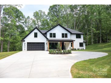 Beautiful two-story home with a black-trimmed roof, black garage door, circle drive, and fresh landscaping at 3415 Waxhaw Indian Trail S Rd, Waxhaw, NC 28173