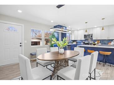 Bright dining area with modern light fixture, stylish table, and adjacent kitchen with blue accents at 3722 Unionville Indian Trail W Rd, Indian Trail, NC 28079