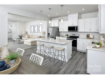 Open concept kitchen features island with seating, stainless steel appliances, and white cabinetry at 7232 Hodges Meadow Ln, Charlotte, NC 28213