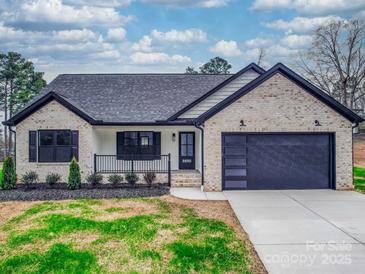 Charming brick home featuring black trim, a modern garage door, and a well-manicured front yard at 8690 Crestwood Dr, Mount Pleasant, NC 28124