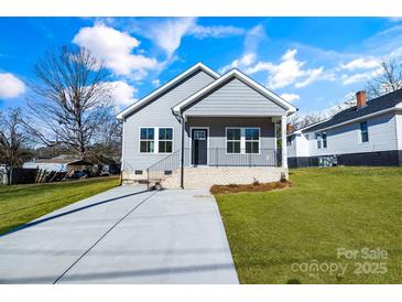 Gray house with a brick base, driveway, and landscaped lawn at 1077 Gibson St, Albemarle, NC 28001