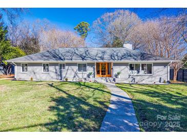 Gray brick ranch home with double wood doors, landscaped lawn, and walkway at 2861 Sharon Rd, Charlotte, NC 28211