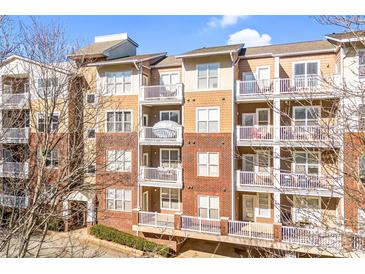 Brick building with multiple units, private balconies, and ample parking at 1000 E Woodlawn Rd # 105, Charlotte, NC 28209