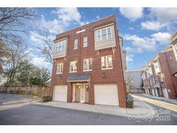 Three story townhome with white garage doors and brick facade at 106 N Laurel Ave # 120, Charlotte, NC 28207