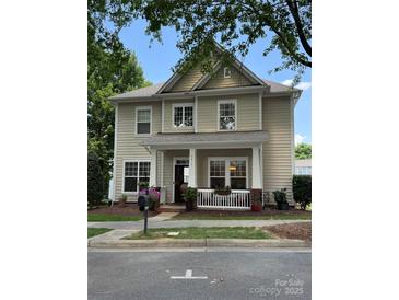 Charming two-story home featuring a cozy front porch and beautifully landscaped front yard, with blue sky in the background at 9415 Rosalyn Glen Rd, Cornelius, NC 28031