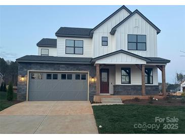 Charming two-story home featuring white siding, a stone facade, and an attached two-car garage at 15004 Brownleigh Ln, Huntersville, NC 28078