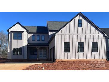 Modern farmhouse style home with board and batten siding, black trim, and a covered front porch at 13944 Roosevelt Grove Dr, Huntersville, NC 28078