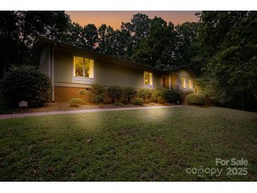 Ranch home with mature landscaping, brick walkway, and inviting nighttime ambiance at 825 W Ketchie St, China Grove, NC 28023