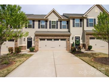 Charming townhome showcasing a well-maintained front yard, gray siding, black shutters and a convenient two-car garage at 138 Lanyard Dr # B, Mooresville, NC 28117