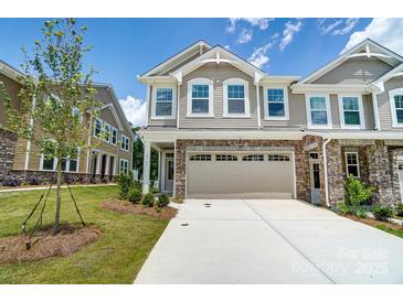Tan two-story townhome with stone accents and a two-car garage at 14930 Tamarack Dr, Charlotte, NC 28278