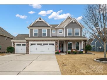 Charming two-story home features a three-car garage and inviting front porch with stone and gray siding at 3332 Delaware Dr, Denver, NC 28037