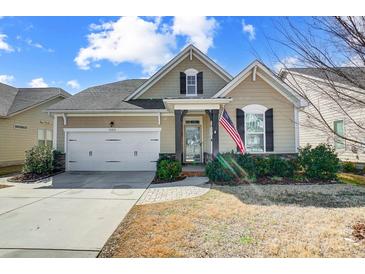 Tan house with white garage door, landscaping, and American flag at 1009 Chapman St, Indian Trail, NC 28079