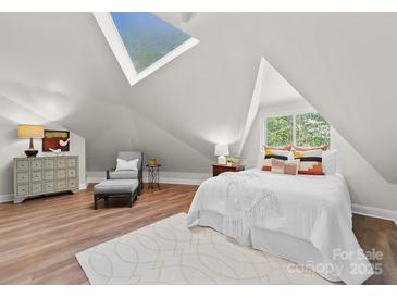 Cozy bedroom under a unique roofline with a skylight, chair, and hardwood floors at 10200 Amsterdam Dr, Mount Pleasant, NC 28124