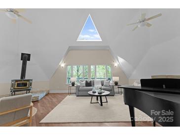Bright living room featuring a vaulted ceiling, wood floors, and a charming wood-burning stove at 10200 Amsterdam Dr, Mount Pleasant, NC 28124
