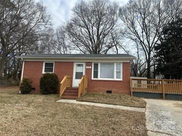 Brick ranch home with a wood deck and a well-maintained lawn at 1219 Stevens Cir, Gastonia, NC 28054