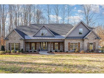 Brick home with gray metal roof, shutters, and a covered porch at 200 Barra Dr, Waxhaw, NC 28173