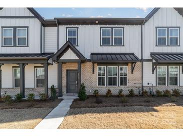 Modern two-story townhome with a brick and white exterior, metal roof accents, and landscaping at 8928 Morning Mist Rd, Charlotte, NC 28215