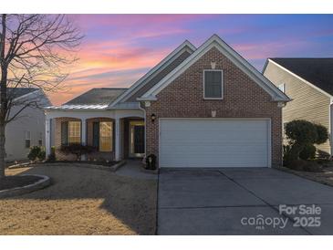 Brick ranch home with attached garage and landscaped lawn at 10318 Threatt Woods Dr, Charlotte, NC 28277