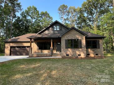 Charming brick home with a well-manicured lawn, covered porch, and attached two-car garage at 305 General As Johnston St, Stanley, NC 28164