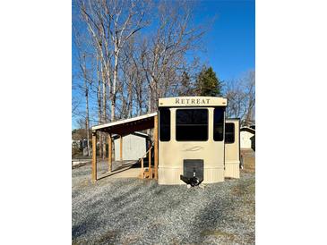 Tan Retreat RV with covered patio and steps at 106 Hummingbird Cir, New London, NC 27281