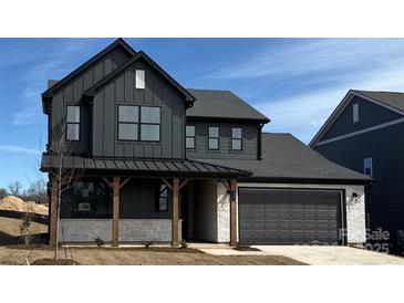 Modern two-story home featuring dark siding, stone accents, a covered porch, and an attached two-car garage at 224 Windy Dell Dr, Tega Cay, SC 29708