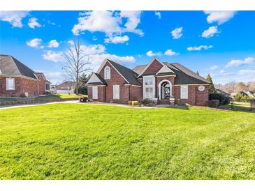 Charming brick home boasts a well-manicured lawn and lovely architectural details under a bright blue sky at 311 Kaitlyn Ln, Kings Mountain, NC 28086