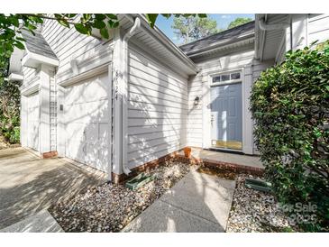Charming home exterior with light-colored siding, attached garage and a welcoming blue front door and stone pathway at 8624 Woodcock Ln, Charlotte, NC 28216