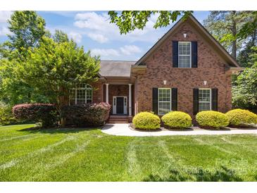 Charming red brick home featuring a beautifully landscaped front yard and classic black shutters at 254 Streamside Pl, Mooresville, NC 28115