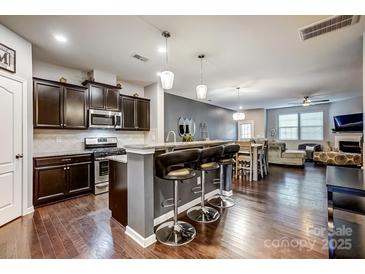 Open kitchen with dark cabinetry, granite countertops, stainless appliances and breakfast bar with pendant lighting at 3033 Honeylocust Ln, Fort Mill, SC 29707