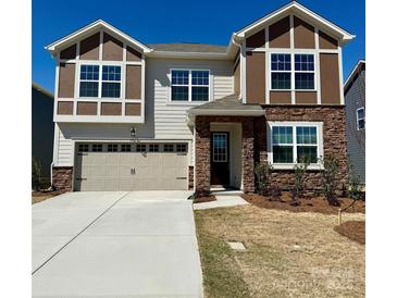 Charming two-story home featuring a stone and siding facade, a two-car garage, and a well-maintained front yard at 1467 Honey Trl, Monroe, NC 28112