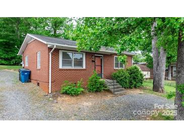 Side view of a brick ranch house with a gravel driveway and green trees at 61 17Th Street Nw Pl, Hickory, NC 28601