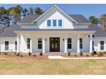 White farmhouse exterior with a wraparound porch and landscaping at 0000 Trull Hinson Rd, Wingate, NC 28174