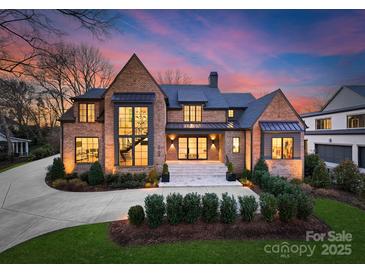 Stunning brick home featuring a manicured lawn, complemented by a well-lit, inviting entrance and tasteful landscaping at 2103 Cortelyou Rd, Charlotte, NC 28211