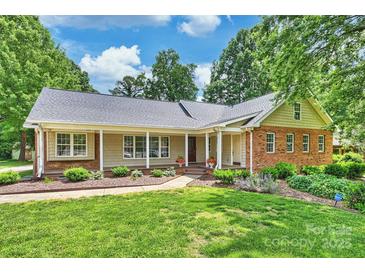 Charming ranch-style home featuring a welcoming front porch, lush lawn, and manicured landscaping at 7135 Folger Dr, Charlotte, NC 28270