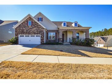 Two-story house with stone and siding exterior, two-car garage, and manicured lawn at 900 Raffaelo Vw, Mount Holly, NC 28120